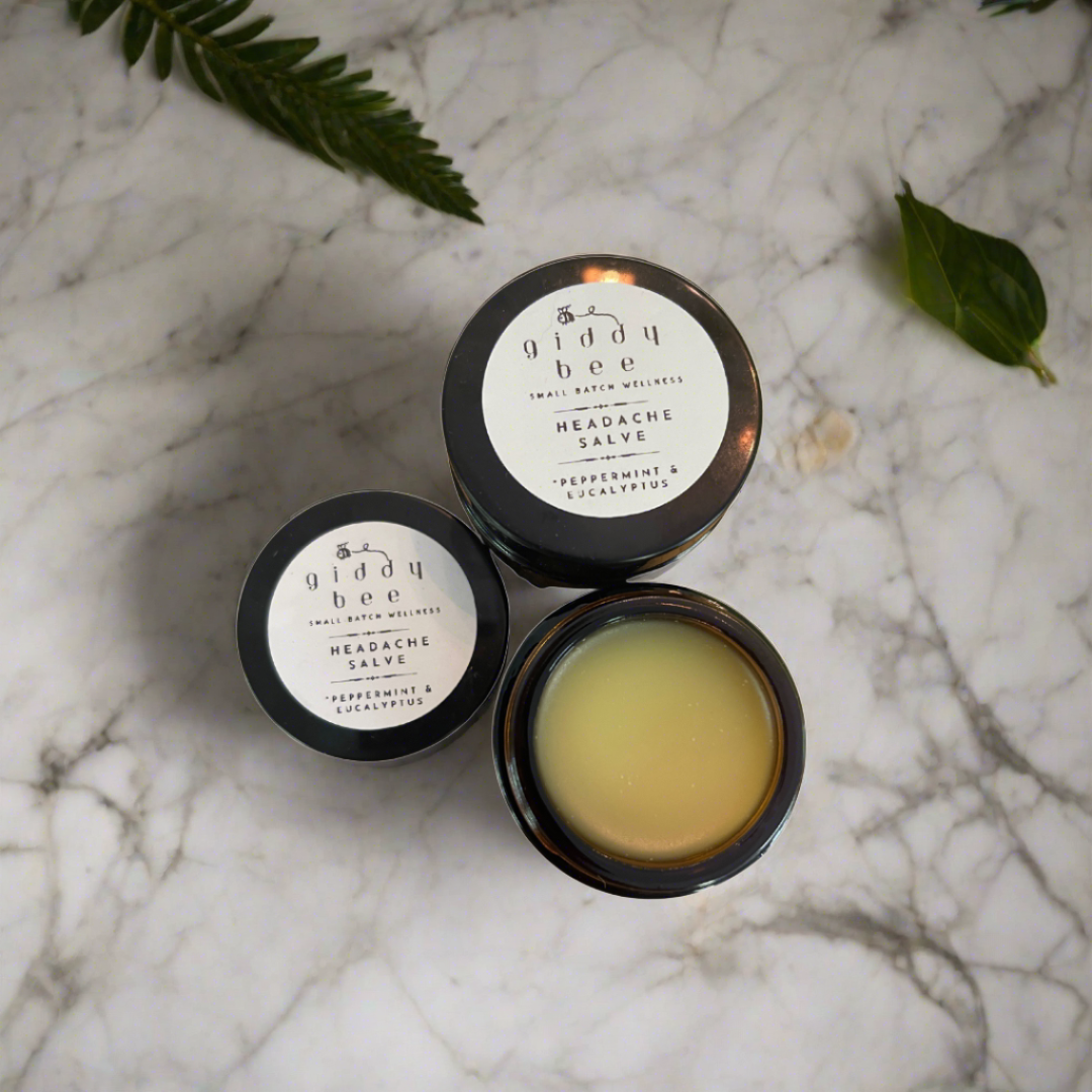 A handcrafted jar of Headache Salve, made with peppermint, spearmint, and eucalyptus-infused oils, beeswax, and shea butter, carefully crafted in small batches by an award-winning South Carolina beekeeper and gardener.